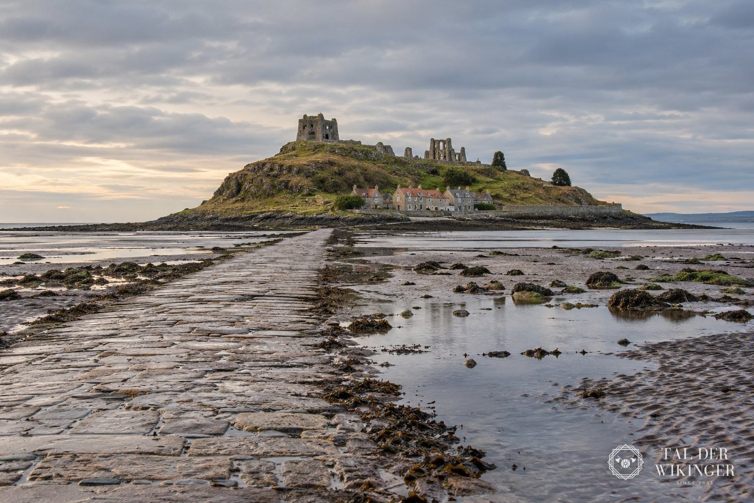 Gezeiteninsel Lindisfarne mit Damm bei Ebbe und Klosterruine im Hintergrund