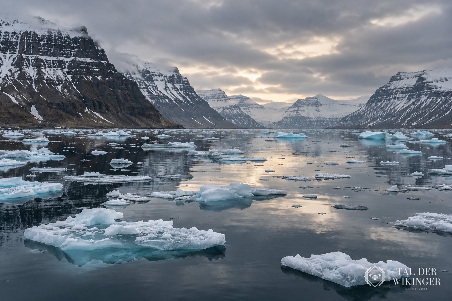 Ruhiger Fjord in den Westfjorden Islands mit Treibeis und schneebedeckten Bergen